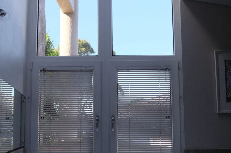 Bathroom uPVC windows with blinds above a jacuzzi bathtub, slanted high light fixed windows up to the skylight above.